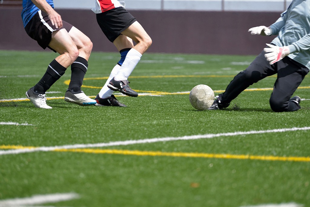 Adult, male, soccer striker, sweeper and goalkeeper going for the ball ** Note: Soft Focus at 100%, best at smaller sizes